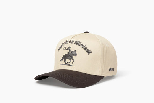 Front 3/4 view of a cream and gray baseball cap with "Nashville or Nashville" text arcing over an embroidered cowboy on a horse logo, plus "1806" on the side.