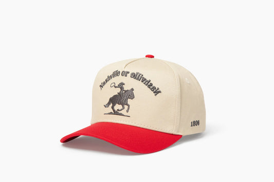 Front 3/4 view of a cream and red baseball cap with "Nashville or Nashville" text arcing over an embroidered cowboy on a horse logo, plus "1806" on the side.