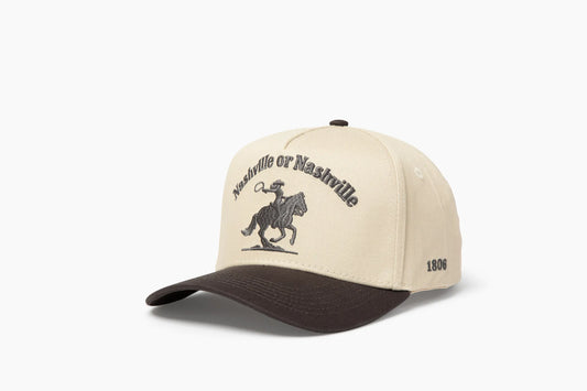 Front 3/4 view of a cream and gray baseball cap with "Nashville or Nashville" text arcing over an embroidered cowboy on a horse logo, plus "1806" on the side.