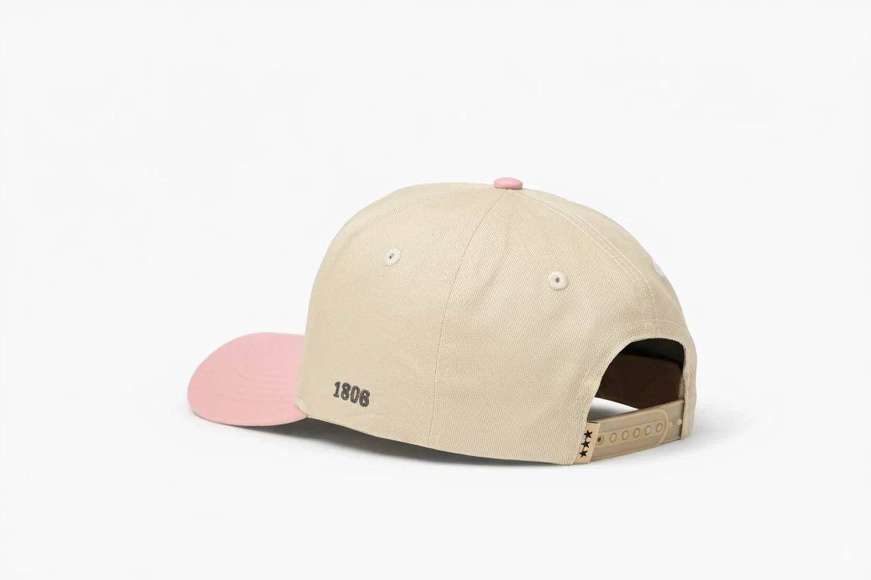 Beige baseball cap with pink brim, featuring "1806" embroidered on the back and three black star details on the adjustable strap. Back view.