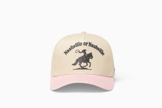 Front view of a beige baseball cap with a prominent pink brim, showcasing "Nashville or Nashville" embroidered above a cowgirl riding a horse graphic.