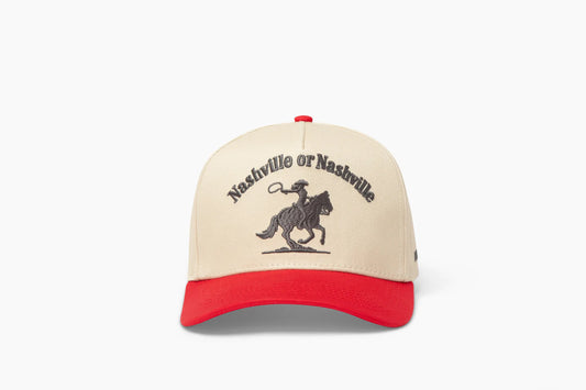 Front view of a beige baseball cap with a prominent red brim, showcasing "Nashville or Nashville" embroidered above a cowgirl riding a horse graphic.