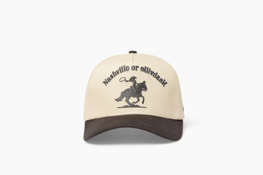 Front view of a beige baseball cap with a prominent gray brim, showcasing "Nashville or Nashville" embroidered above a cowgirl riding a horse graphic.
